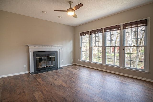 Empty room with dark brown wooden floors, a black fireplace, and tall white windows