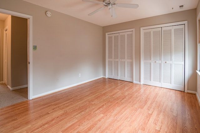 Empty room with light wooden floors, beige walls, and white closet doors