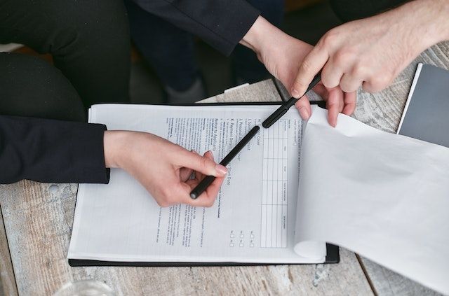 Hands holding a black pen and reviewing a form on a clipboard
