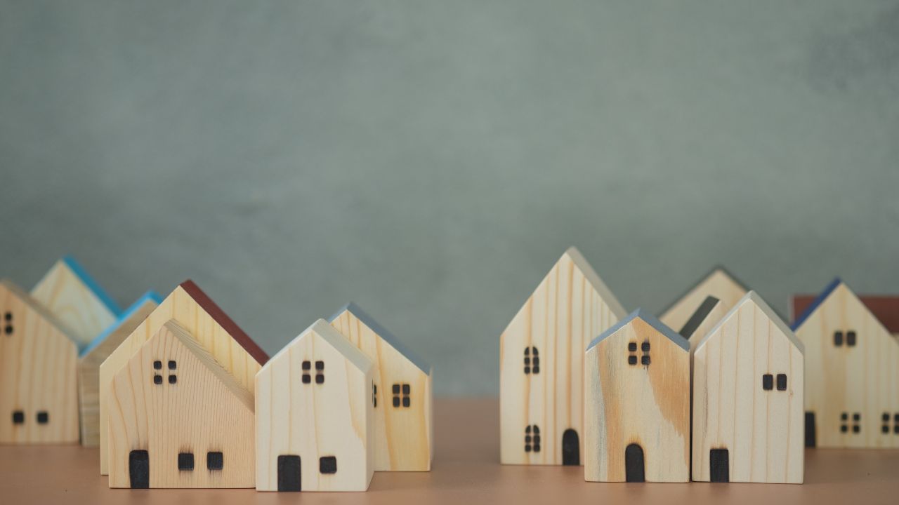 Six small wooden houses lined up on a table
