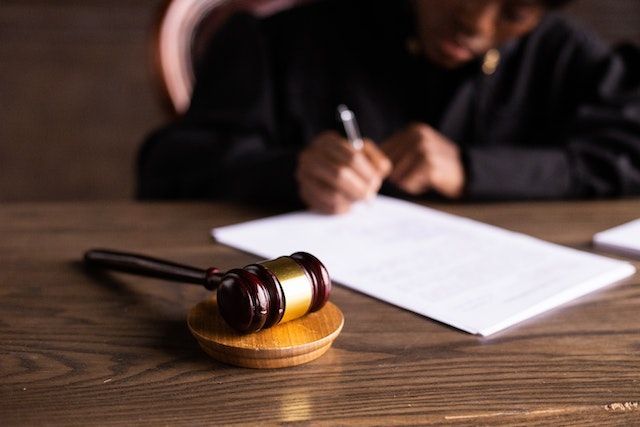 Person taking notes on a piece of paper, a gavel on their desk
