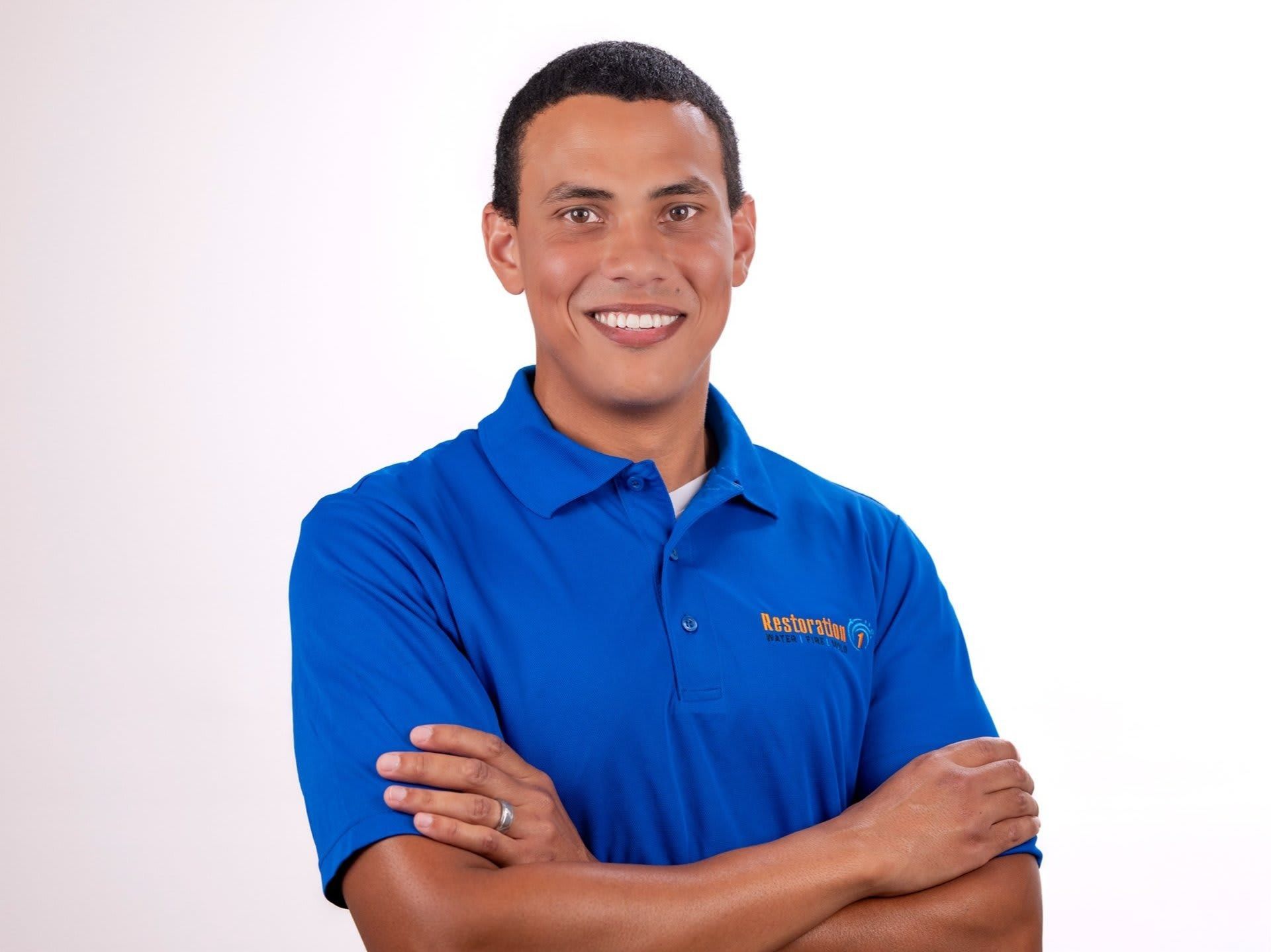 Smiling person in a blue polo shirt with arms crossed on a white background