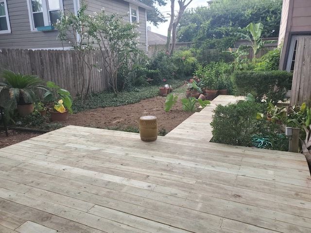 A wooden deck with a stool on it in the backyard of a house.