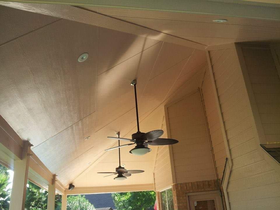 Two ceiling fans are hanging from the ceiling of a porch