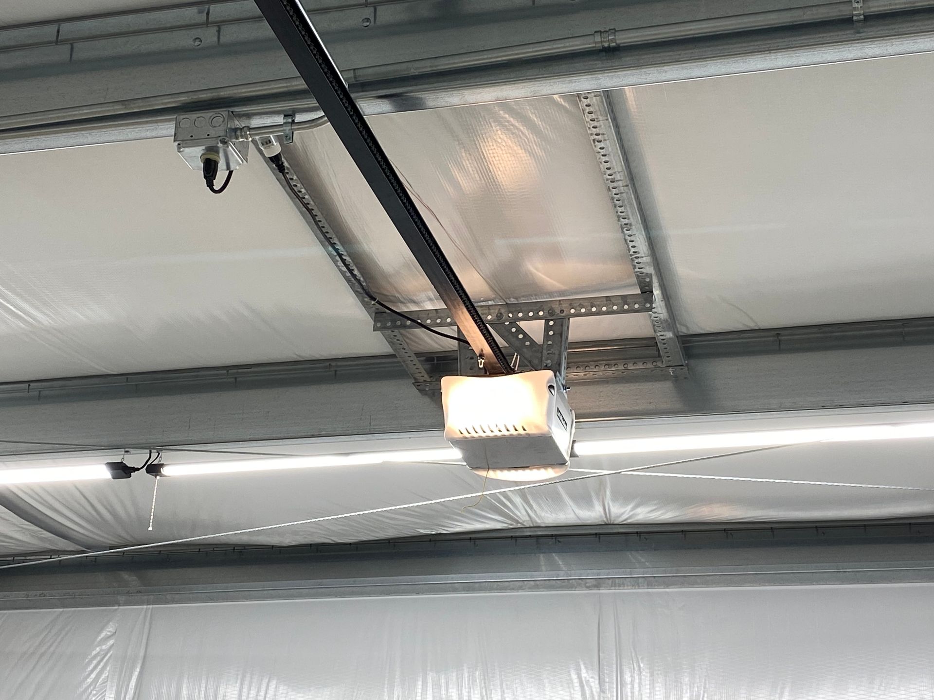 A garage door opener is hanging from the ceiling of a building.