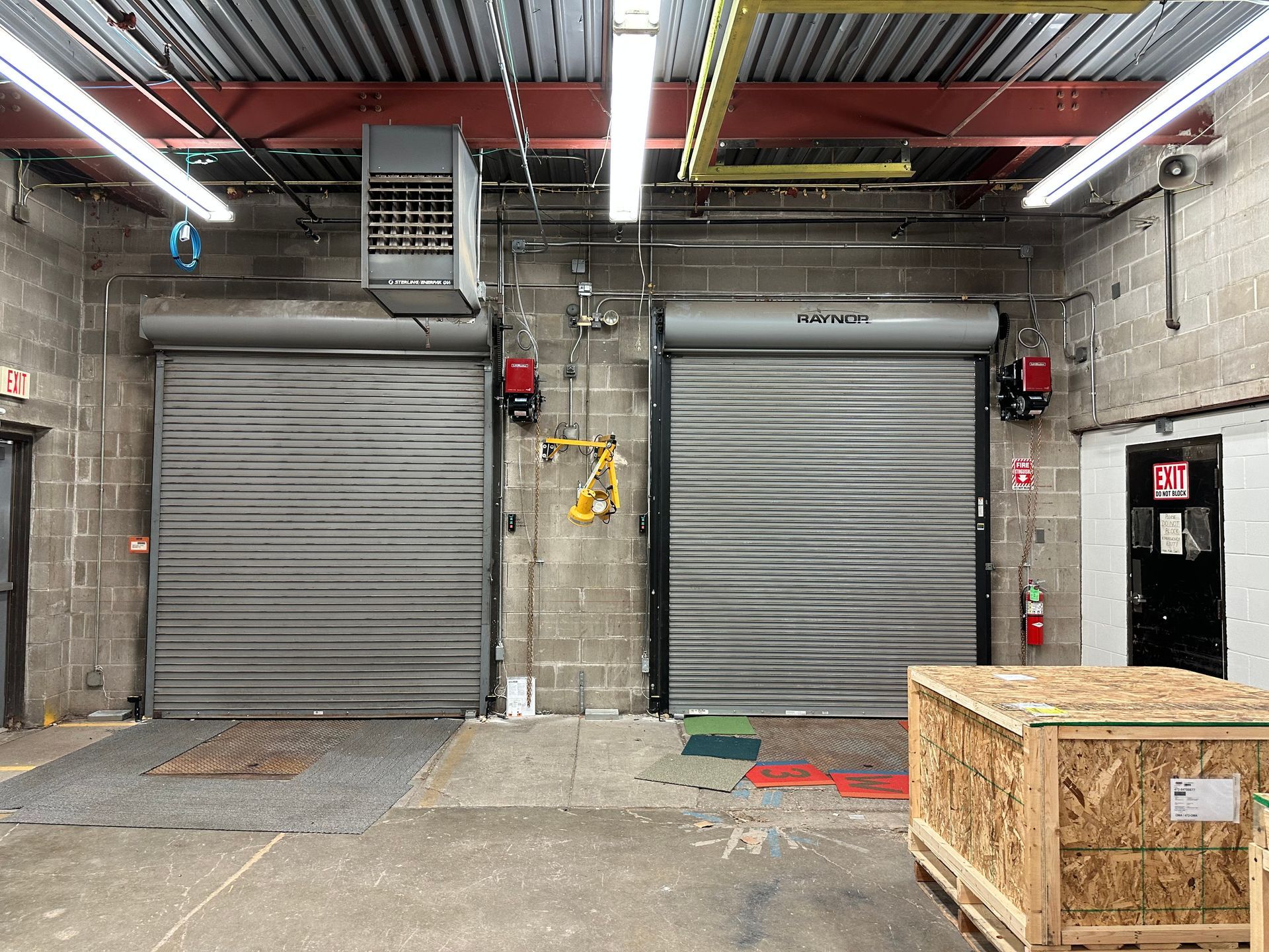 A warehouse with two garage doors and a wooden box in the middle.