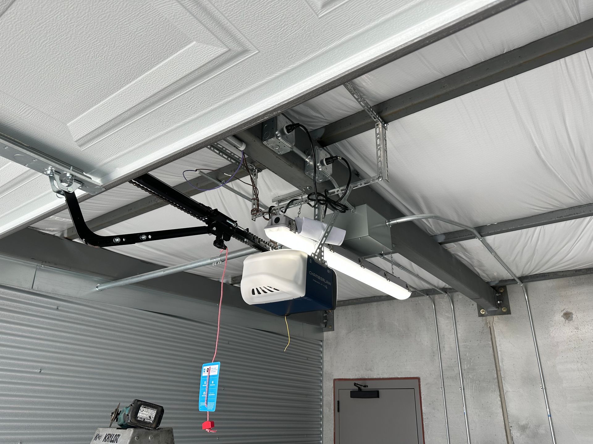 A garage door opener is hanging from the ceiling of a garage.