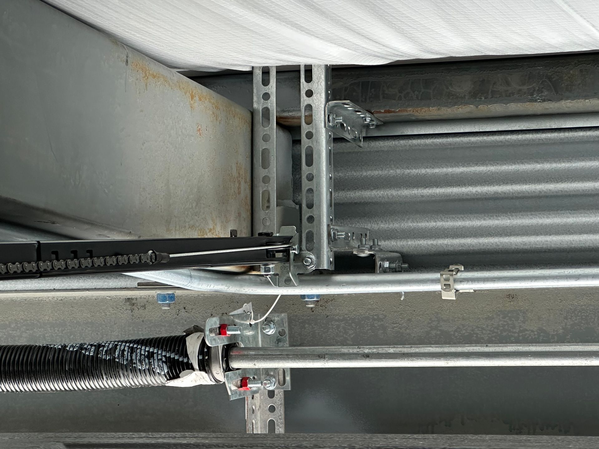 A close up of a garage door spring hanging from the ceiling.