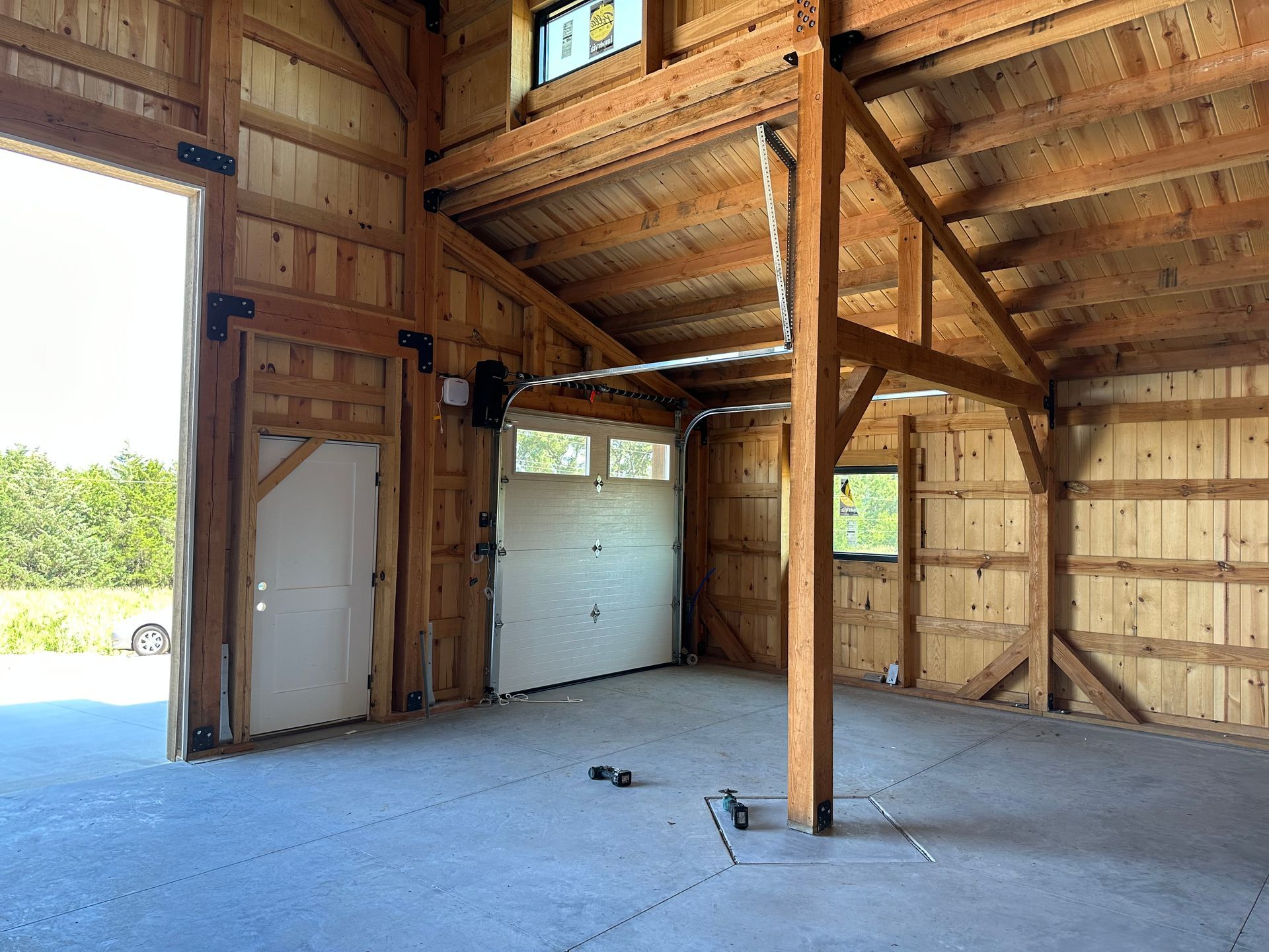 The inside of a wooden barn with a garage door open.