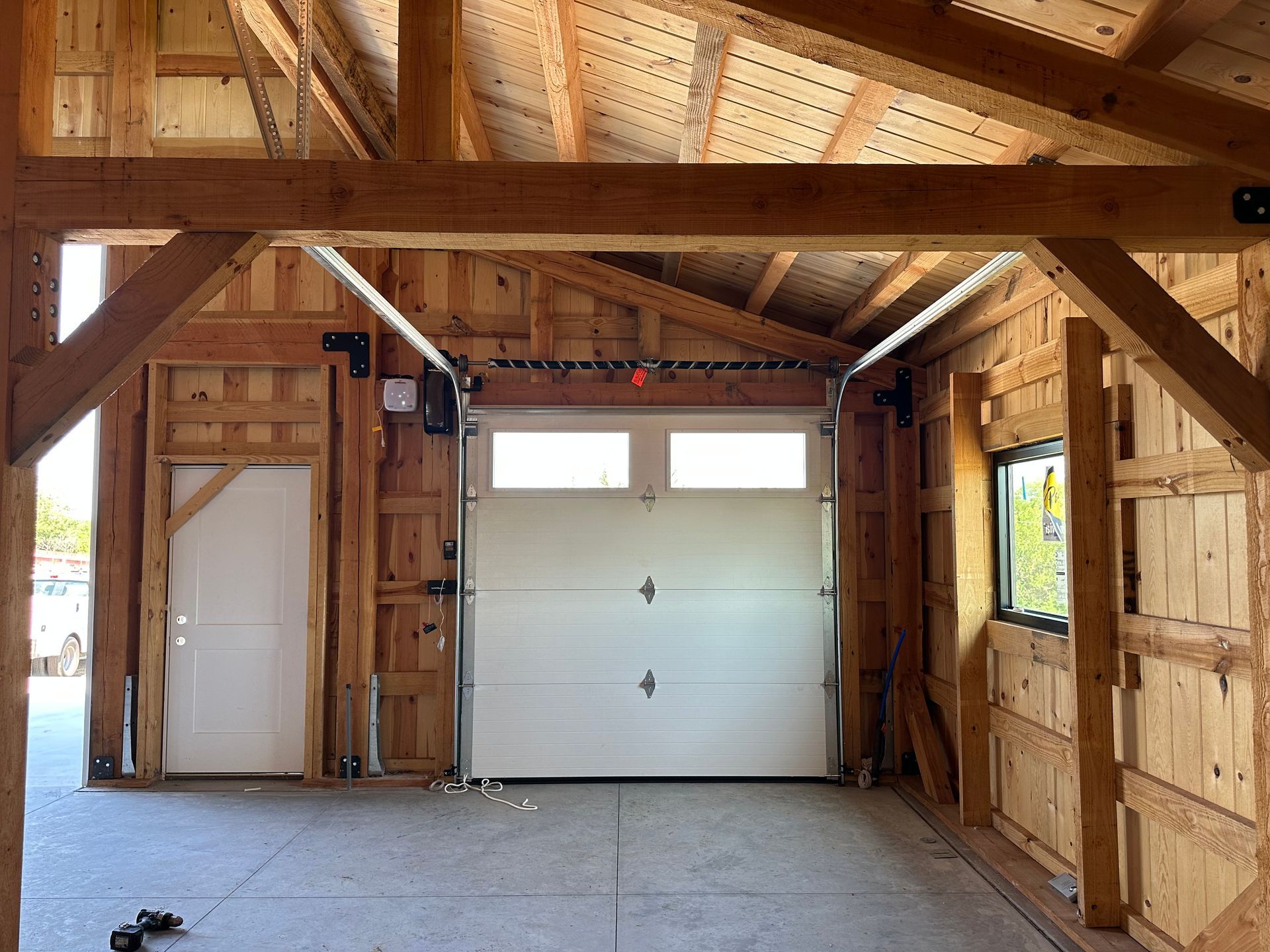 A wooden garage with a white garage door and a white door