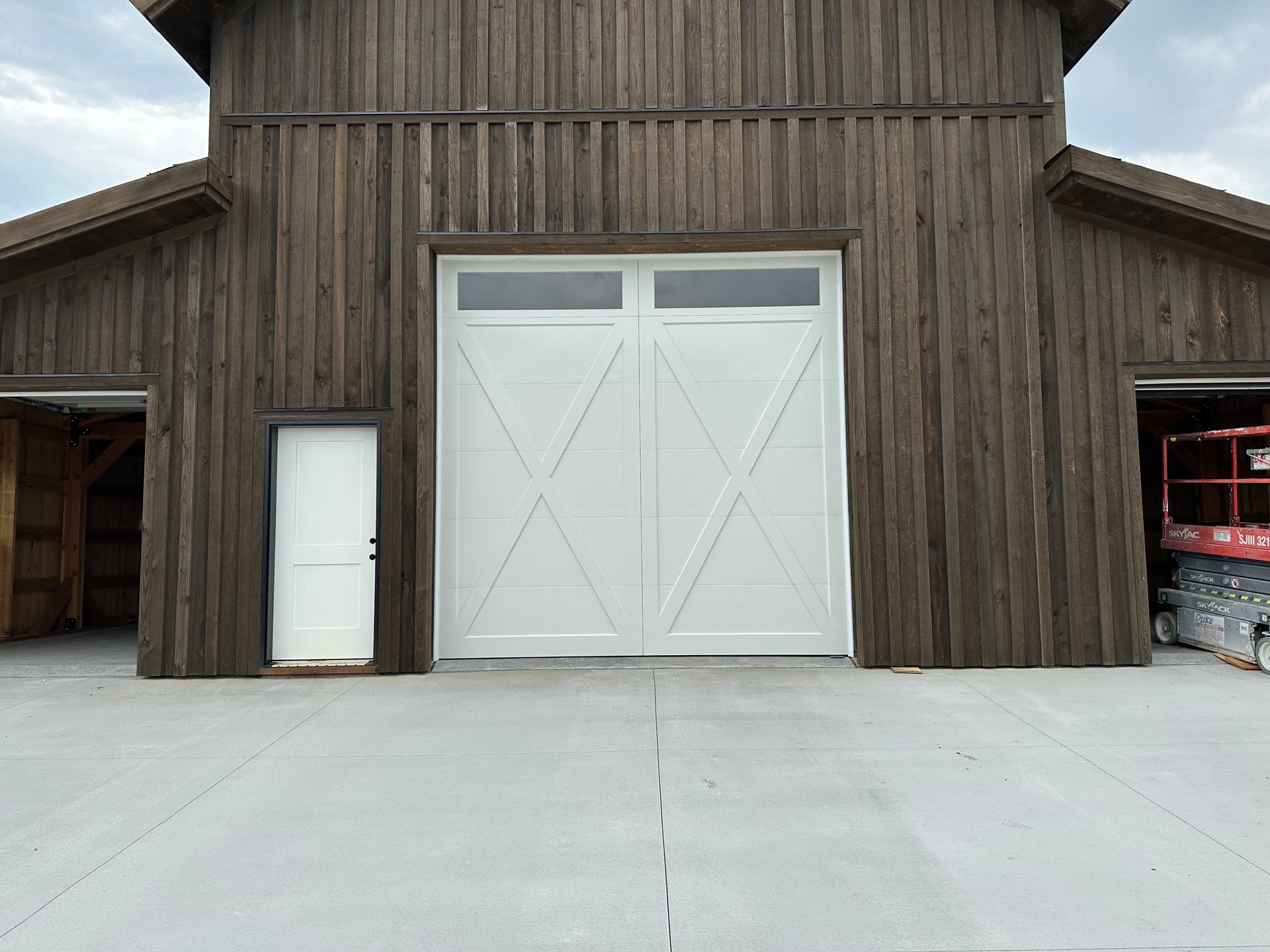 A large barn with a white door and a concrete driveway