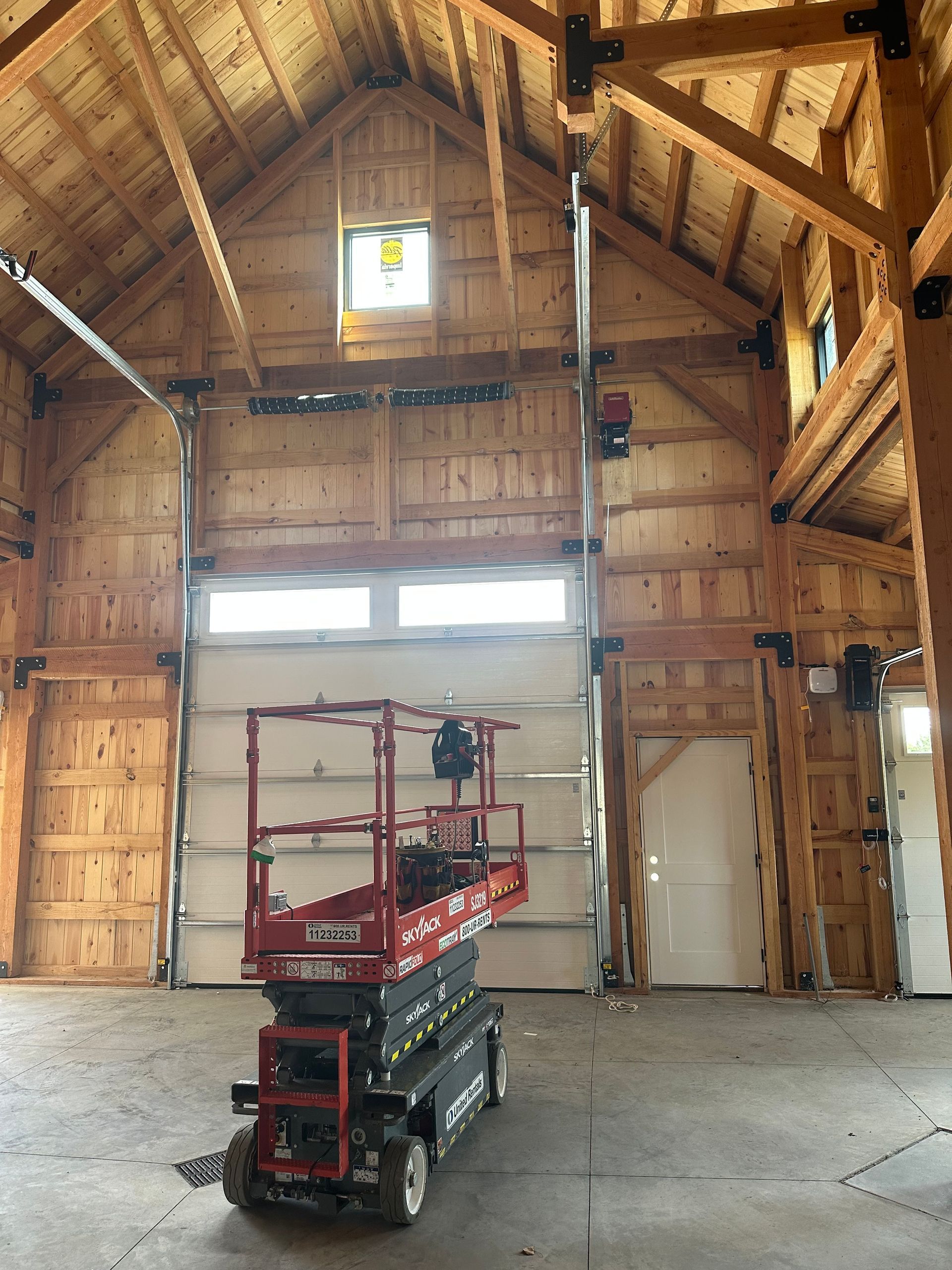 A red scissor lift is parked in a large wooden building.