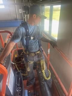 A man is standing on a crane in front of a window.