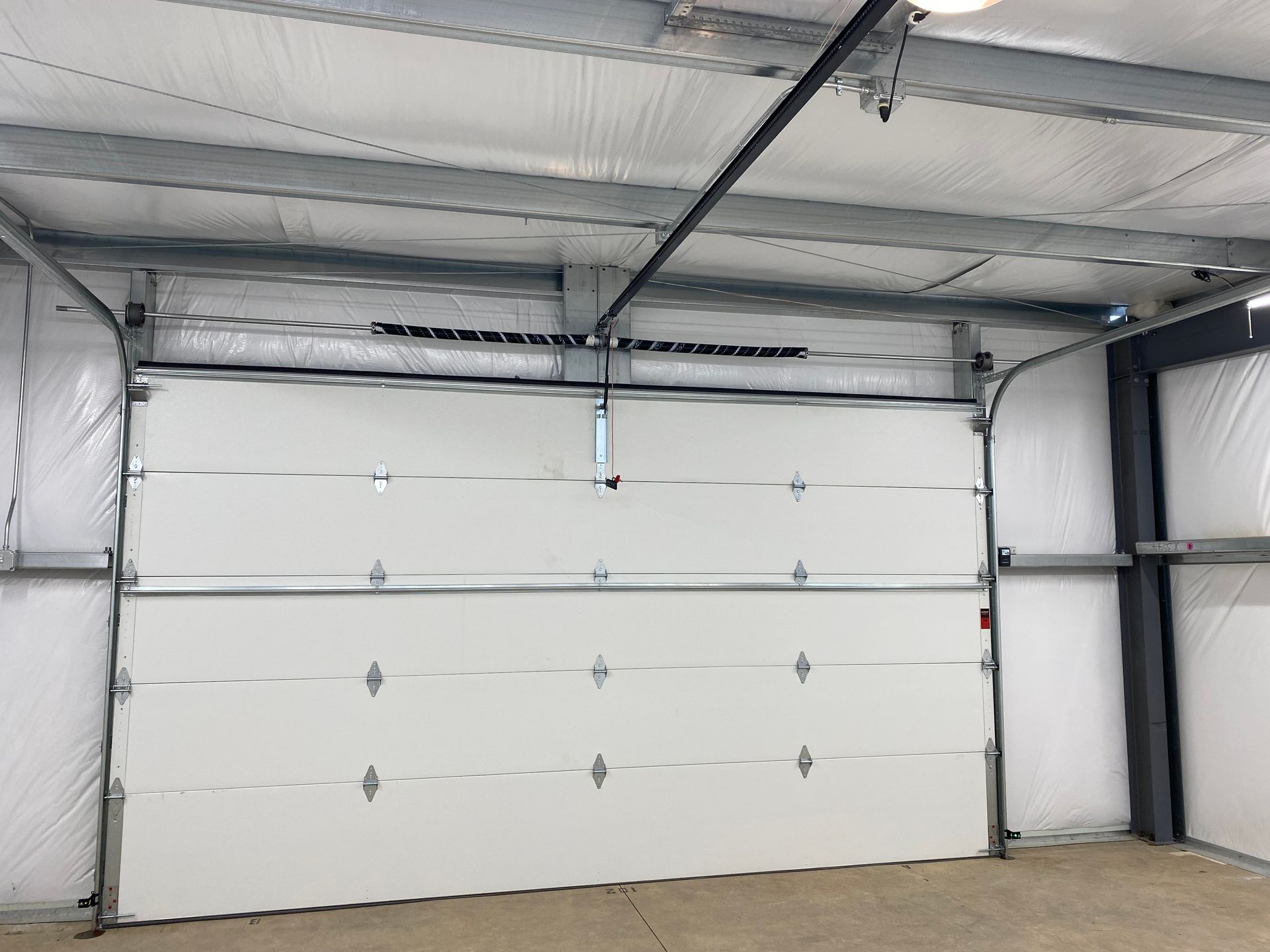 A white garage door is open in a building.