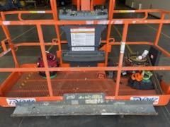 A close up of an orange scissor lift with a cage around it.
