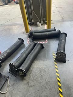 A bunch of black pipes are laying on the ground in a garage.