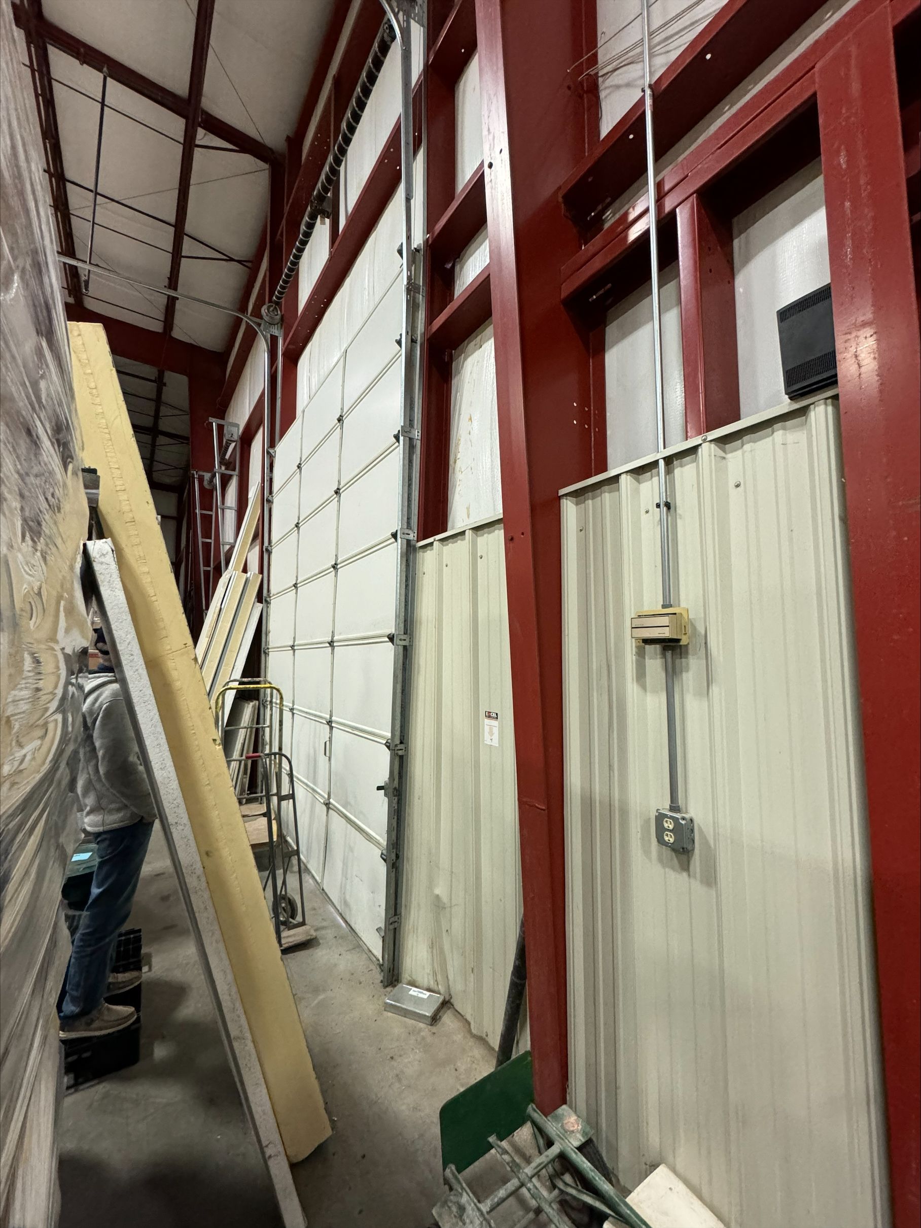A man is standing next to a large garage door in a building.