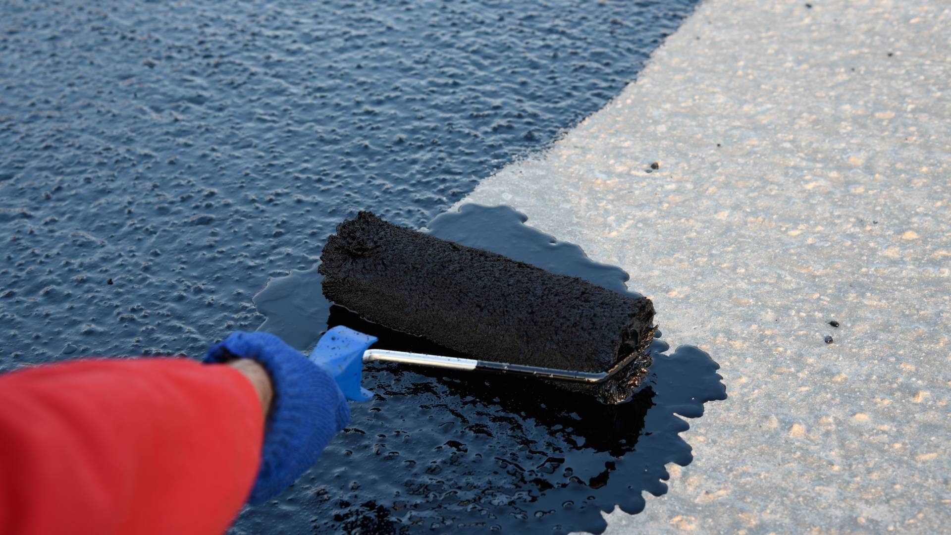 A person is painting a concrete surface with a roller.