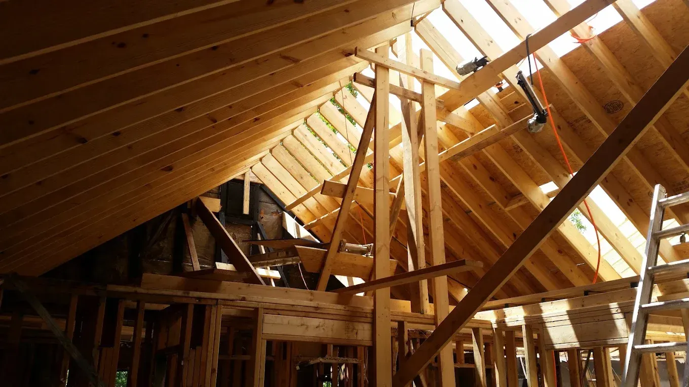 A house is being built with wooden beams and a ladder.