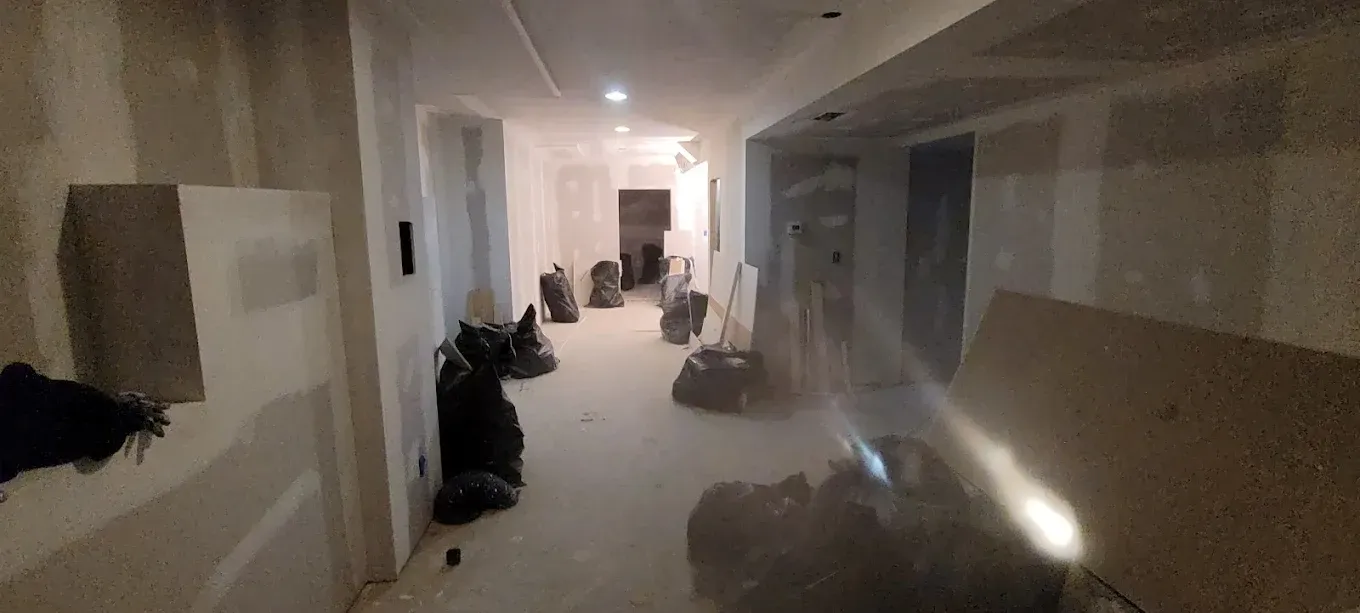 A hallway in a building under construction with a lot of bags on the floor.