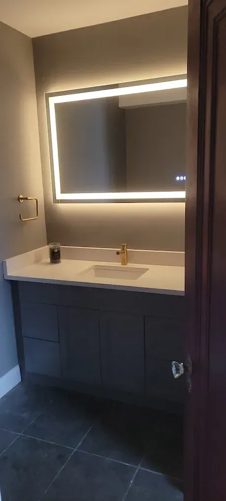 A bathroom with a sink and a mirror with lights on it.