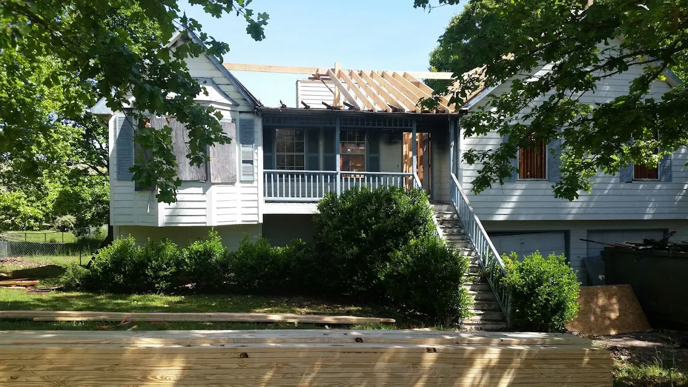 A white house with a blue porch is being remodeled.