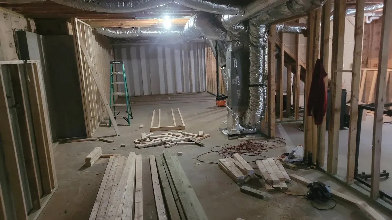A basement under construction with a lot of wood and a ladder.