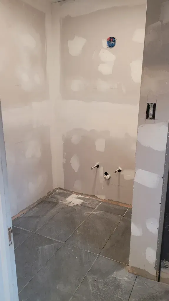 A bathroom under construction with tile floors and drywall.