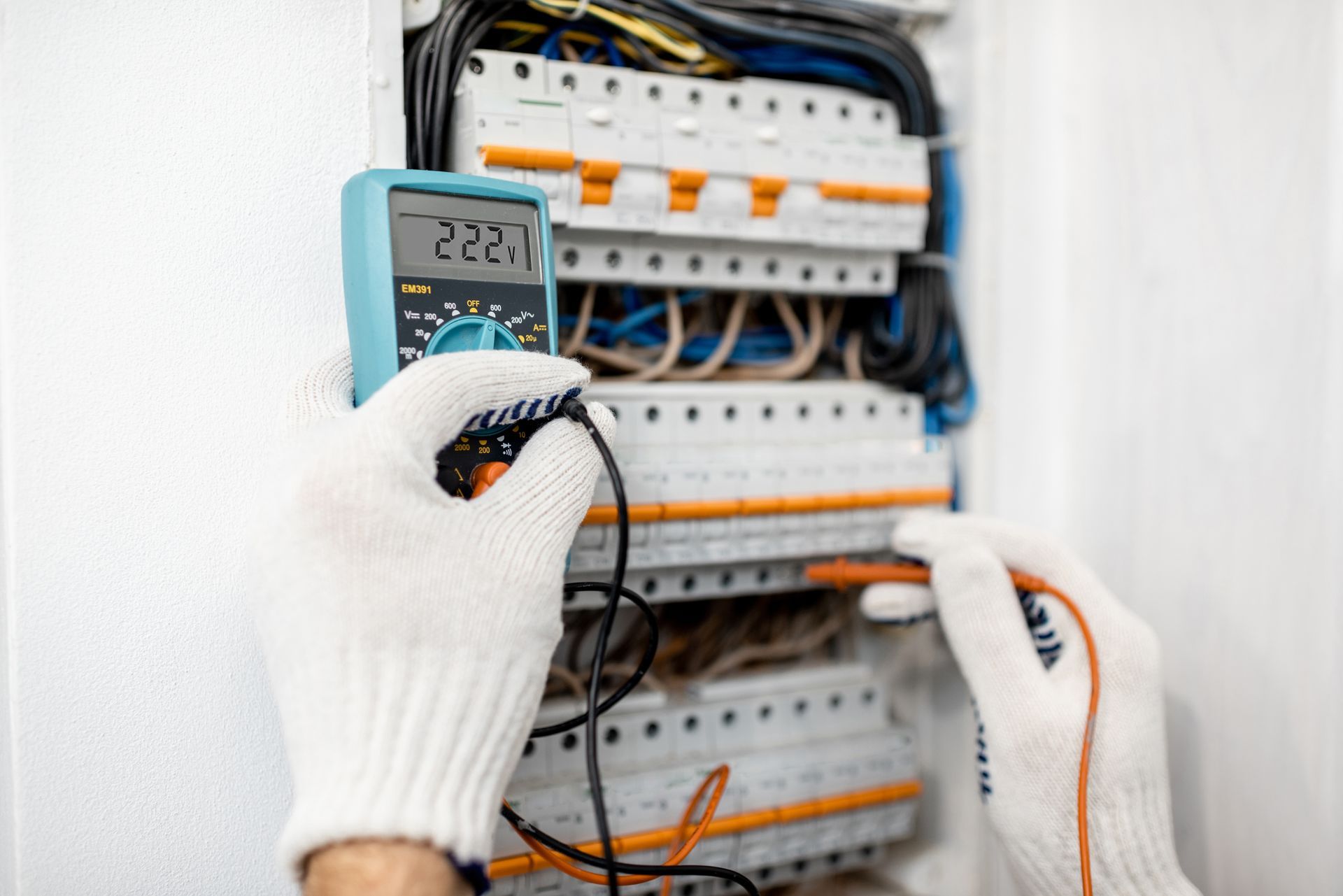 Technician testing electrical panel wiring with a digital multimeter