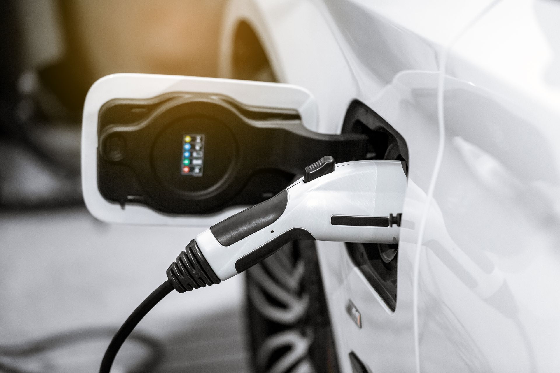 Electric car plugged into a charging station with a white charging cable