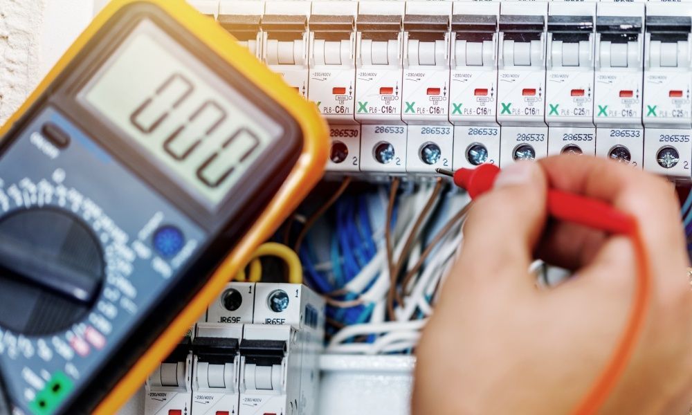 A Person is Using a Multimeter to Test a Circuit Board — Anderson Electrical & Air in Hallidays Point, NSW