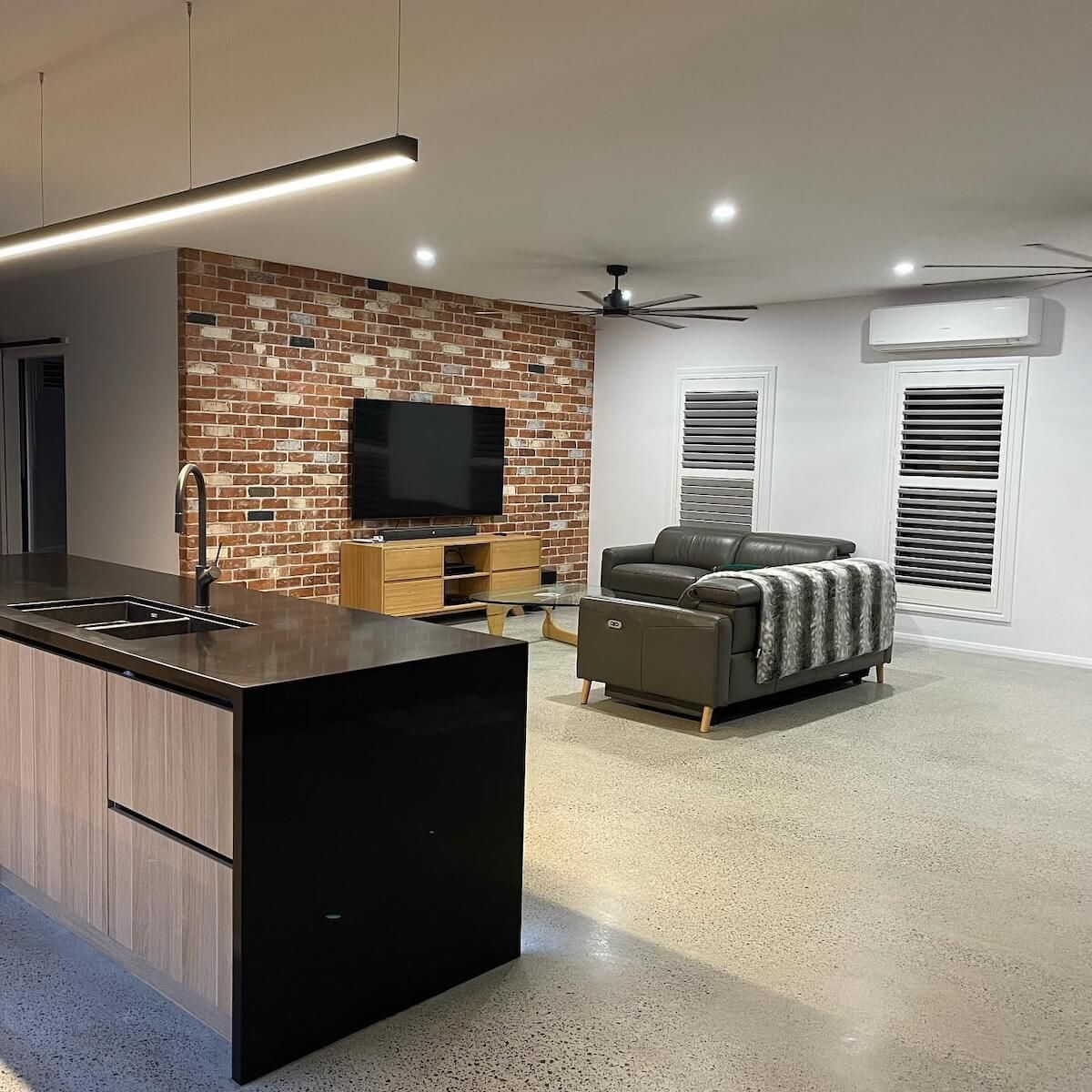 A person is holding a remote control in front of an air conditioner — Anderson Electrical & Air in Taree, NSW
