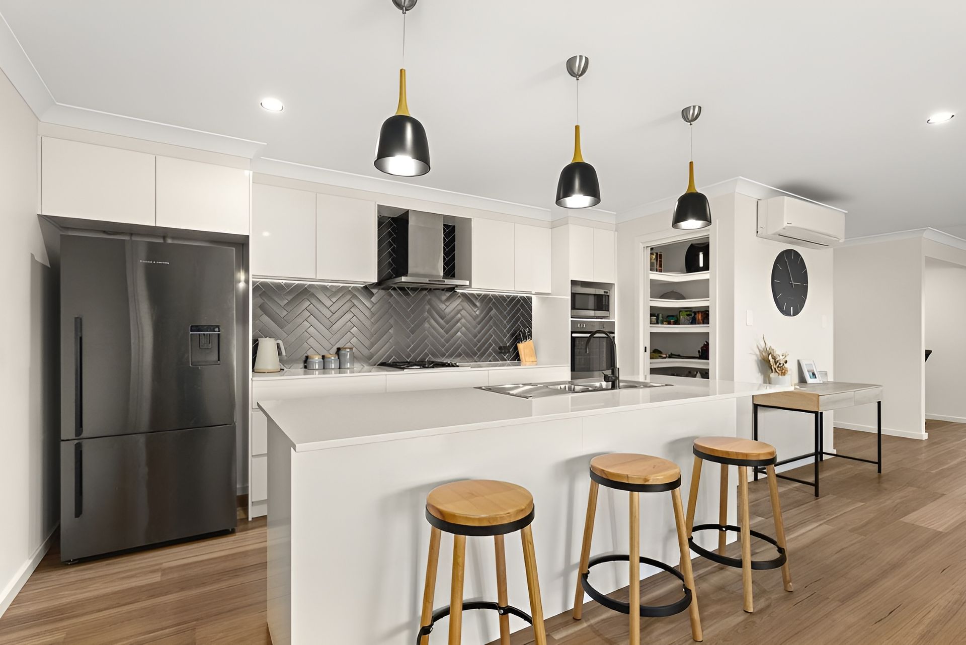 A Kitchen With White Cabinets, Stools, a Refrigerator and a Sink — Anderson Electrical & Air in Taree, NSW