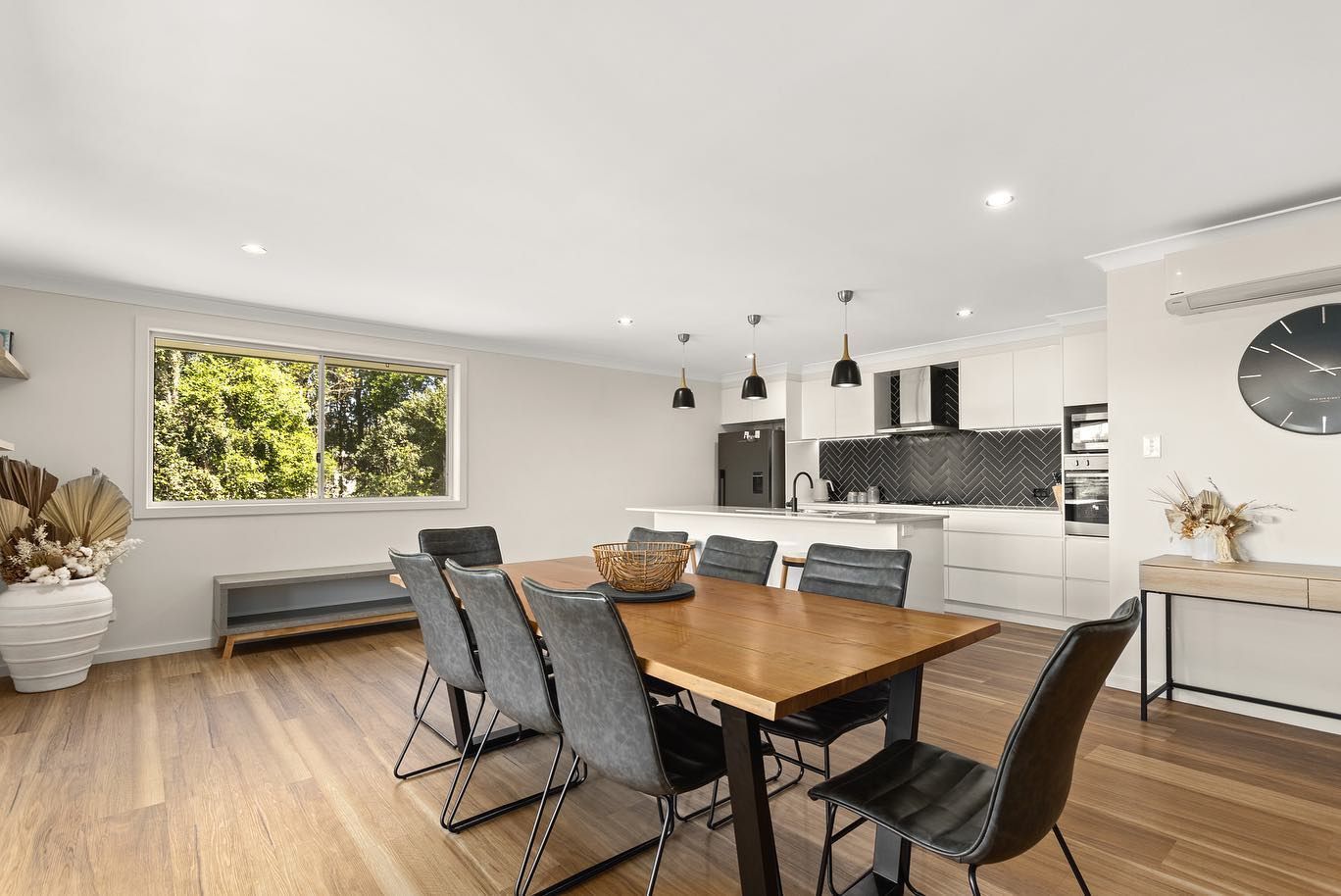 A Dining Room With a Wooden Table and Chairs and a Kitchen — Anderson Electrical & Air in Wingham, NSW
