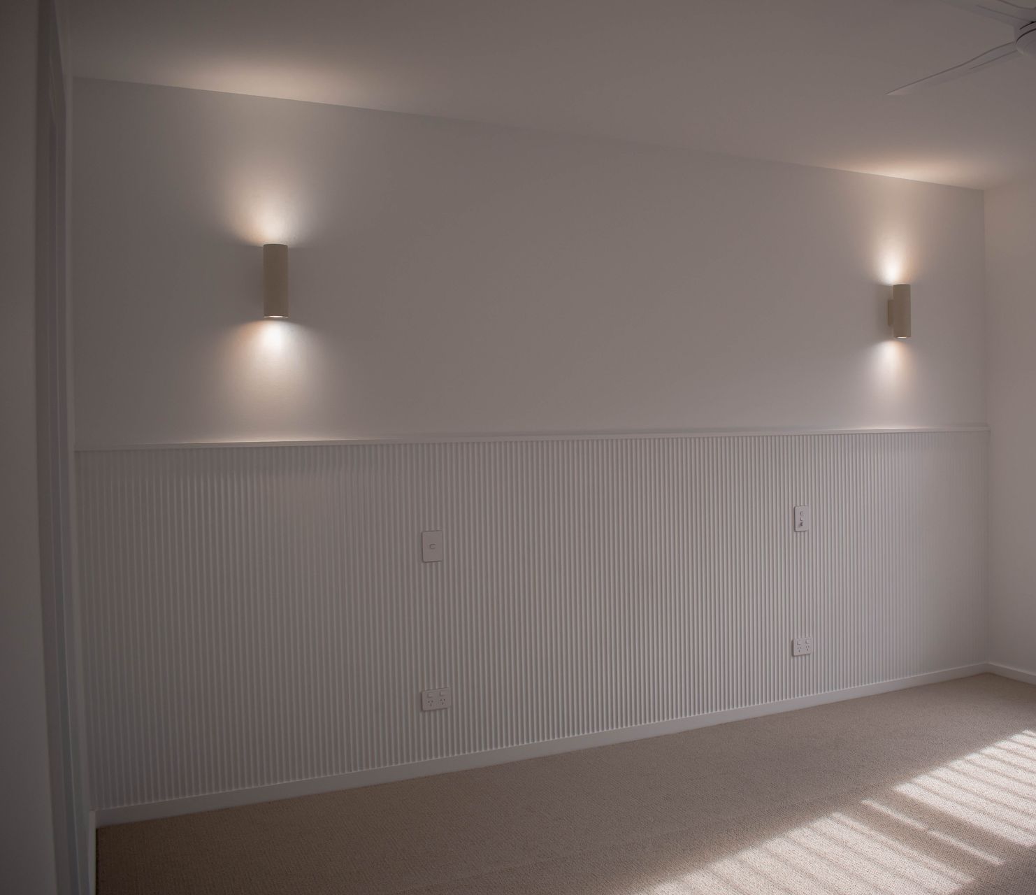 A man is using a multimeter to test a light switch on a wall — Anderson Electrical & Air in Taree, NSW
