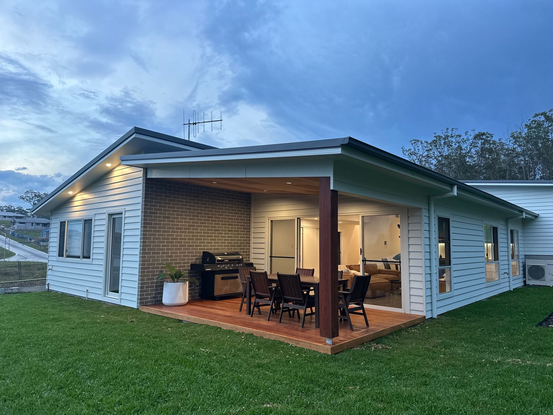 A white house with a patio and a table and chairs in front of it — Anderson Electrical & Air in Taree, NSW