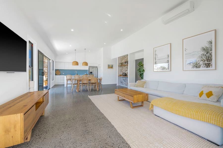 A Man is Fixing an Air Conditioner on a Brick Wall — Anderson Electrical & Air in Taree, NSW