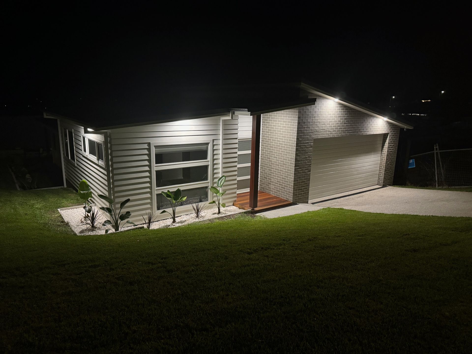 A house with a garage is lit up at night — Anderson Electrical & Air in Taree, NSW