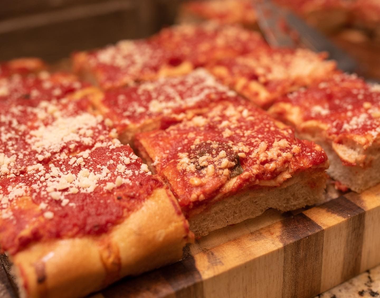 A pizza with tomato sauce and cheese is sitting on a wooden cutting board.