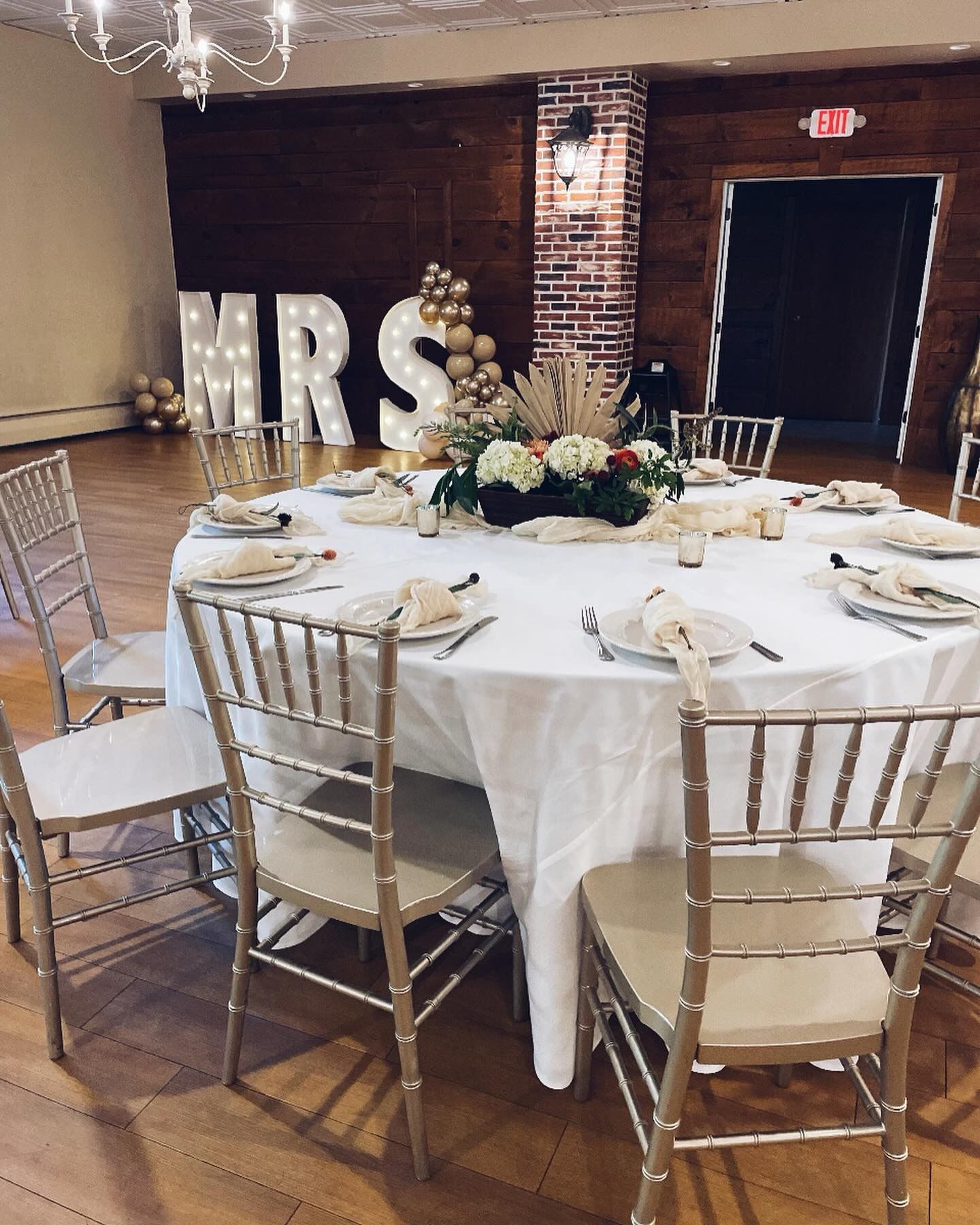A round table with a white tablecloth and chairs is set up for a wedding reception.