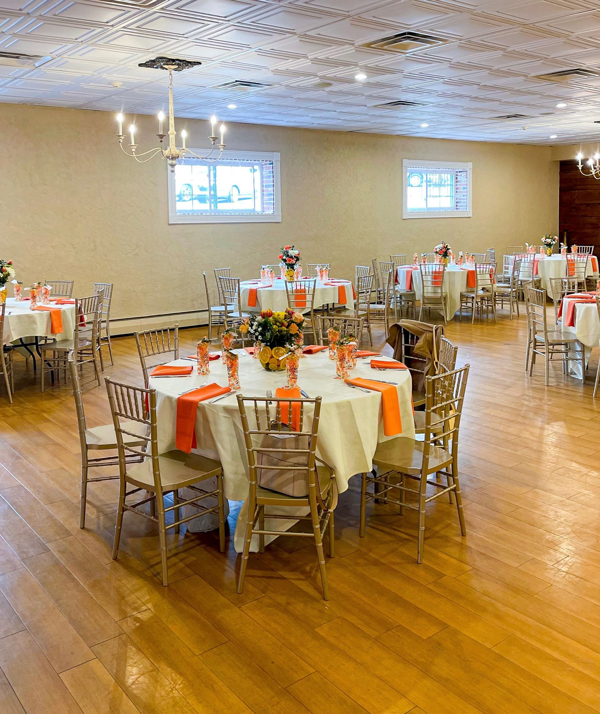 A large room with tables and chairs set up for a wedding reception.