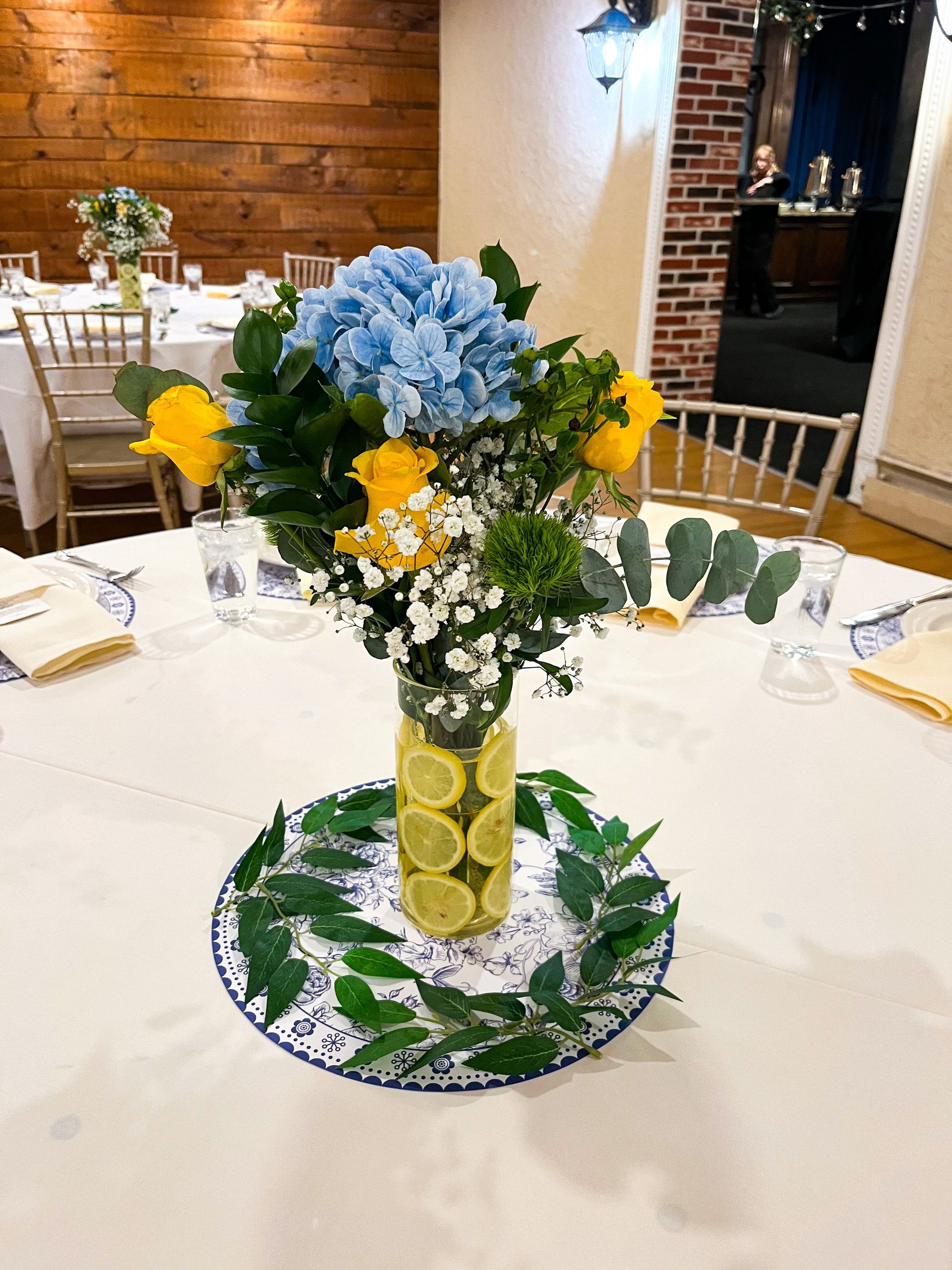 A table with a vase of flowers and lemons on it.