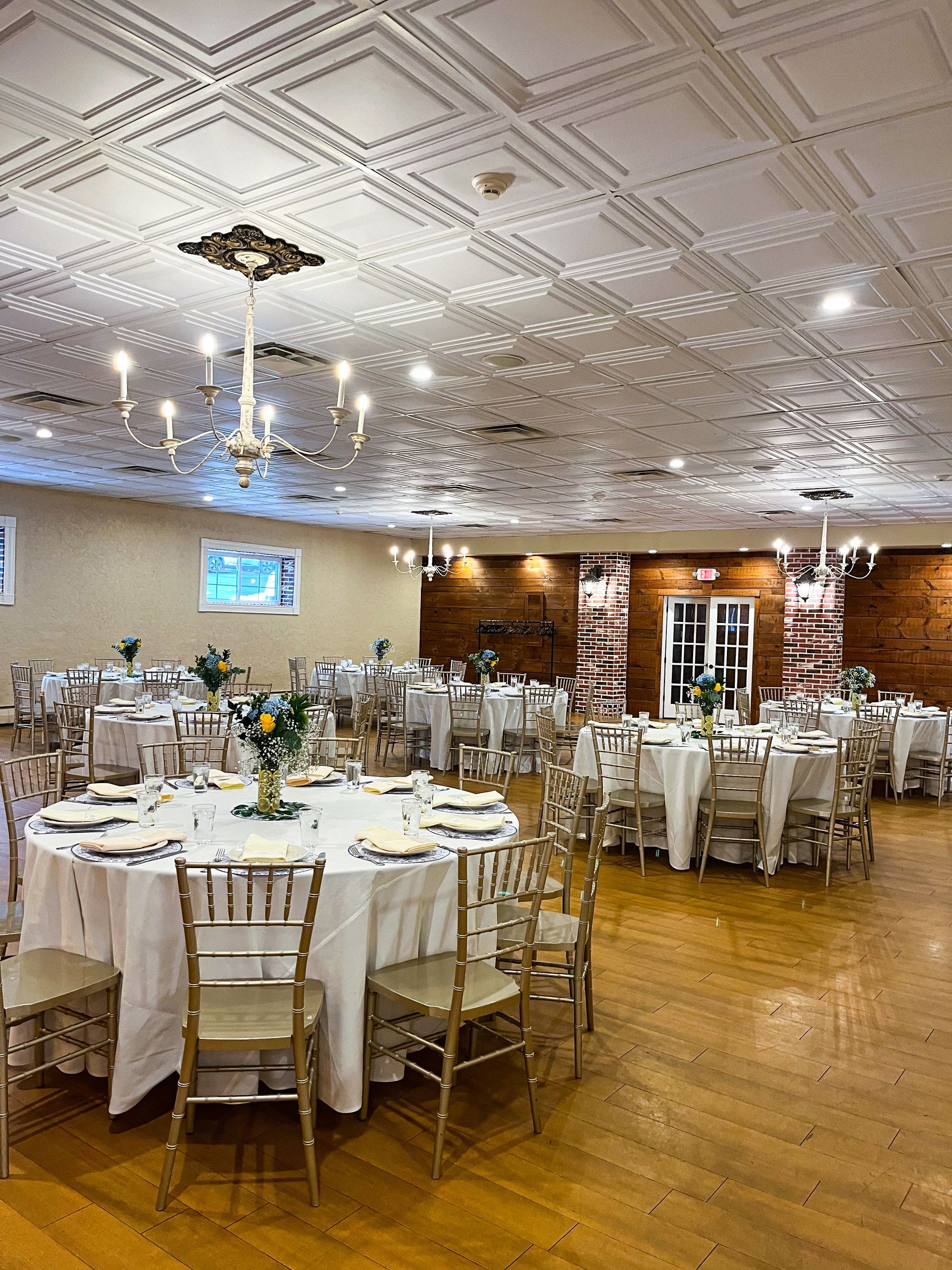 A large room with tables and chairs set up for a wedding reception.
