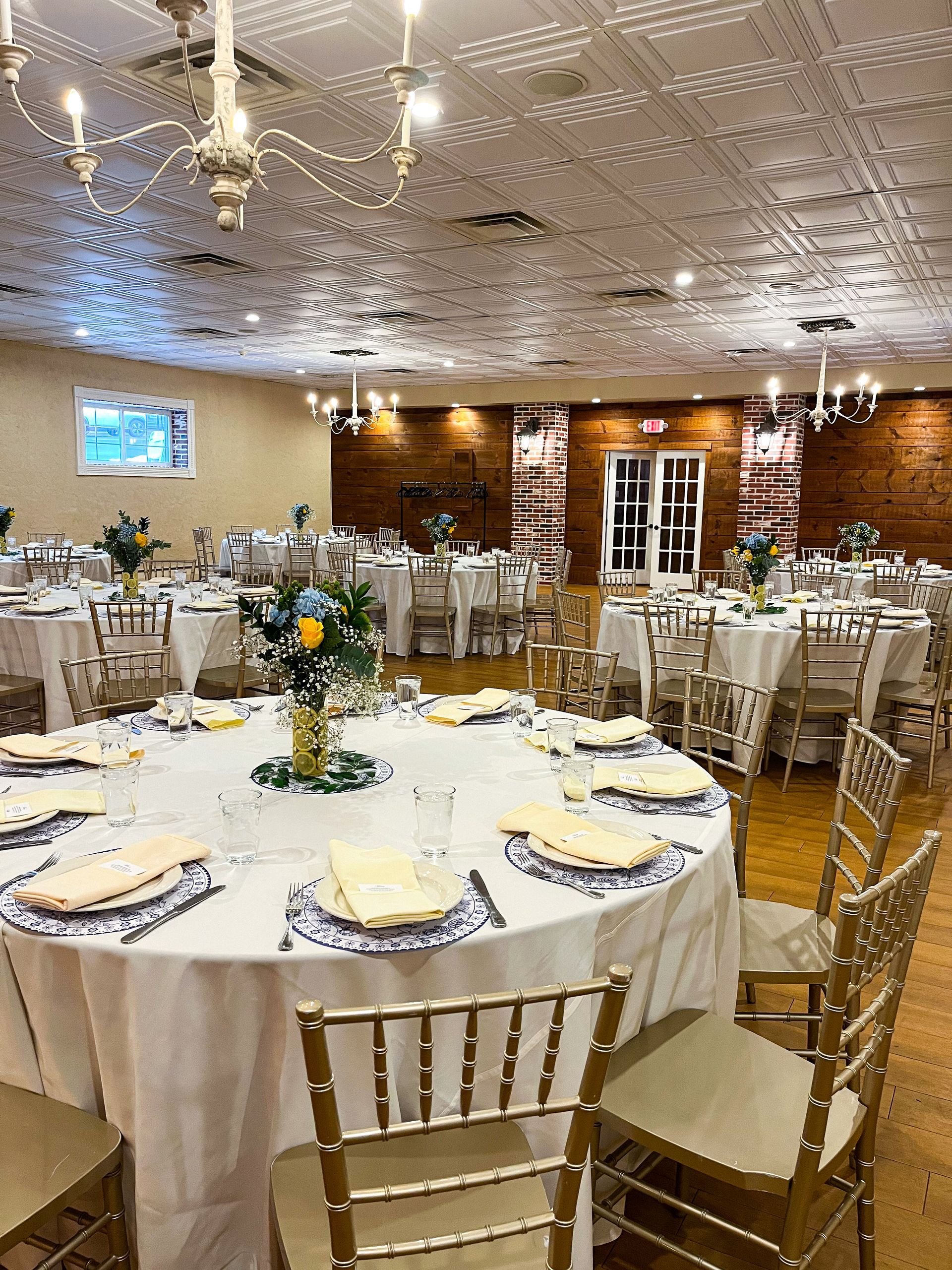 A large room filled with tables and chairs set up for a wedding reception.