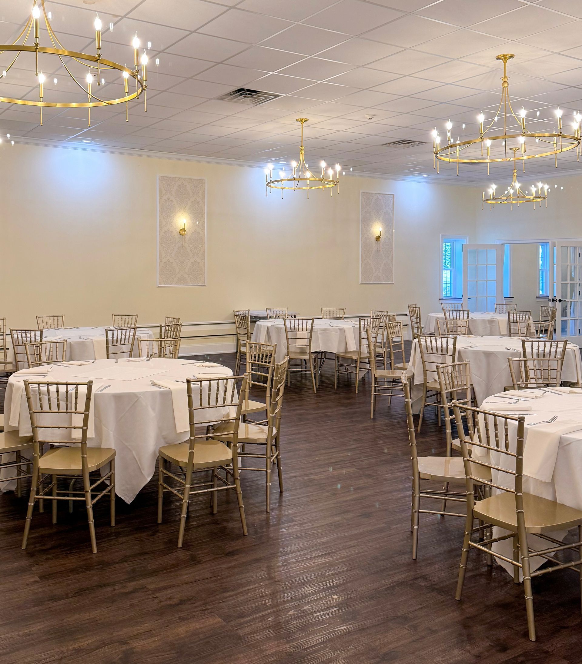 A large room with tables and chairs set up for a wedding reception.