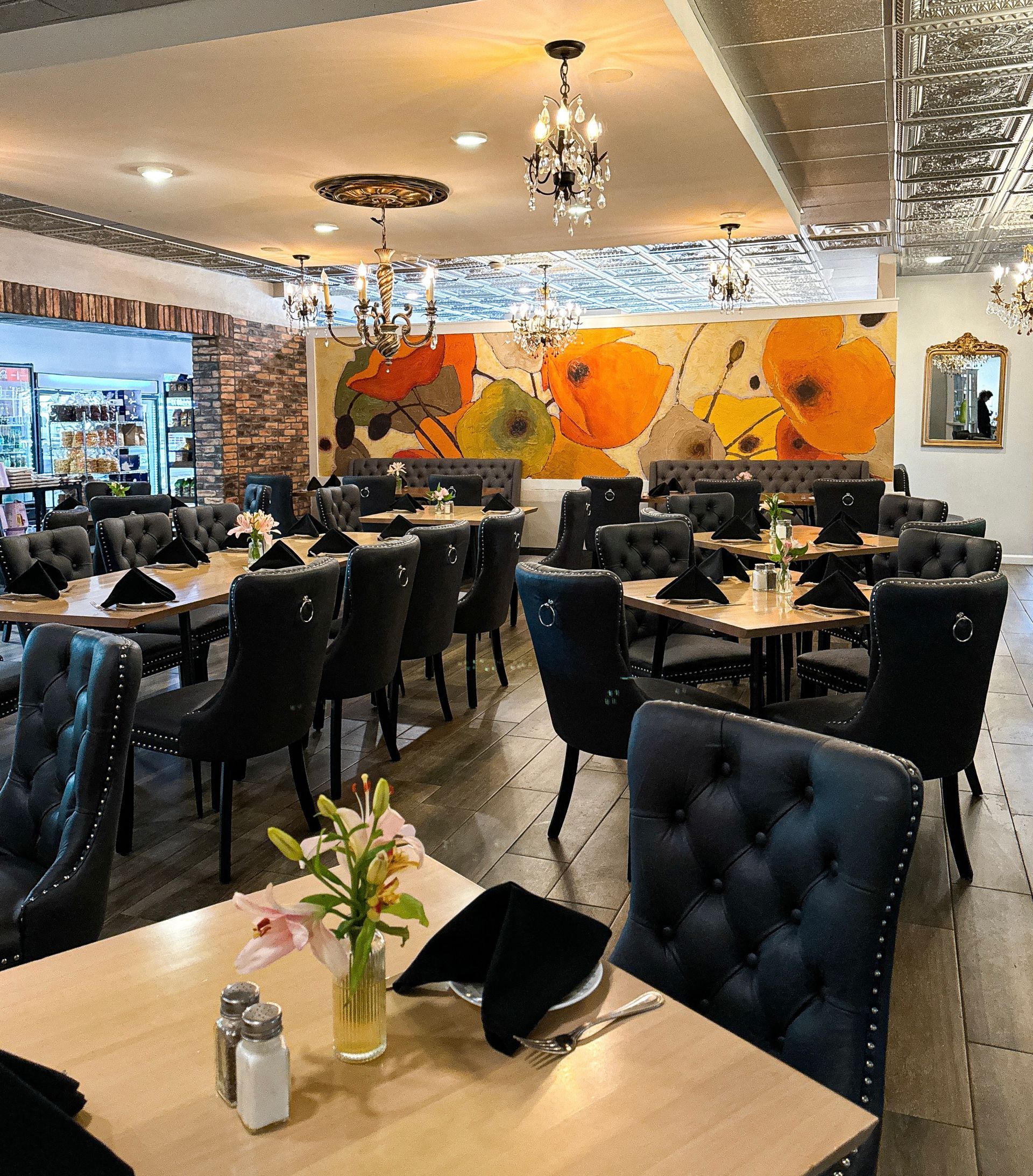 A restaurant with tables and chairs and a wall with flowers on it