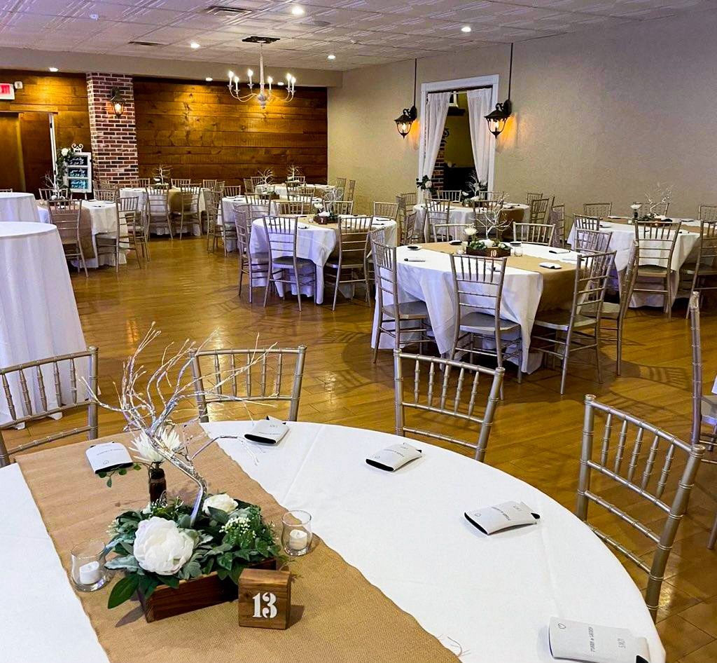 A large room with tables and chairs set up for a wedding reception.