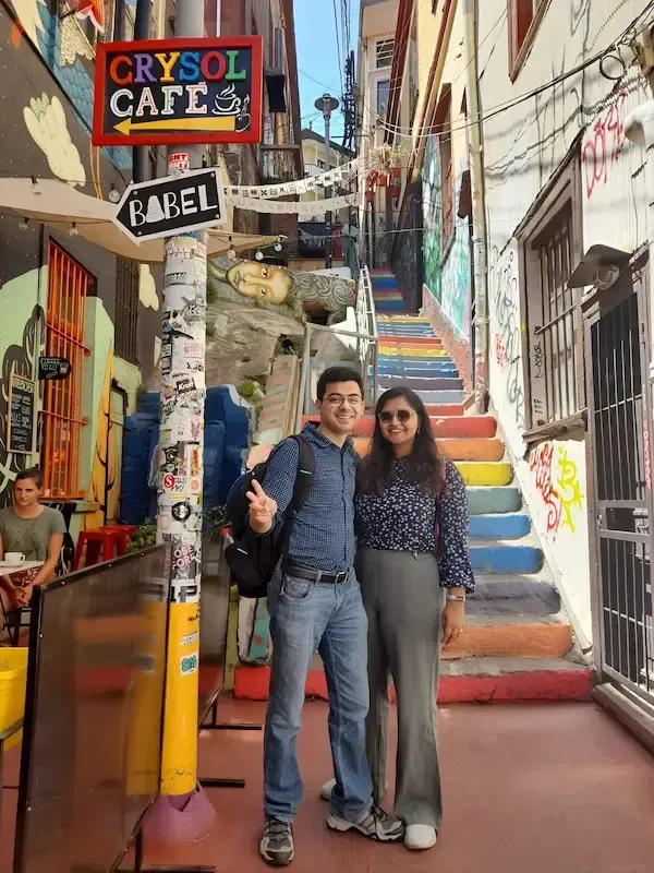 A happy woman posing in the middle of a colorful bird mural on a wall during the walk through Valparaiso with ChileVive Tours.