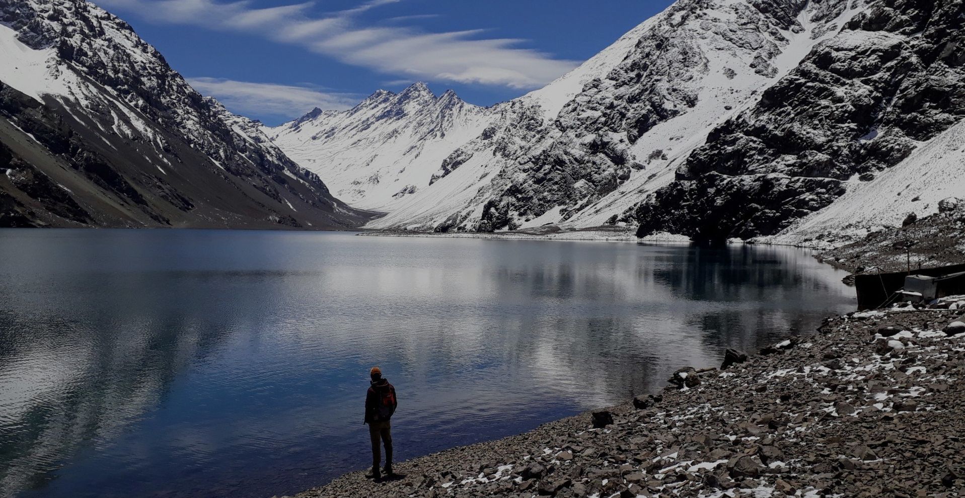 A man looking at the Laguna del Inca and the mountains at the Portillo winter resort