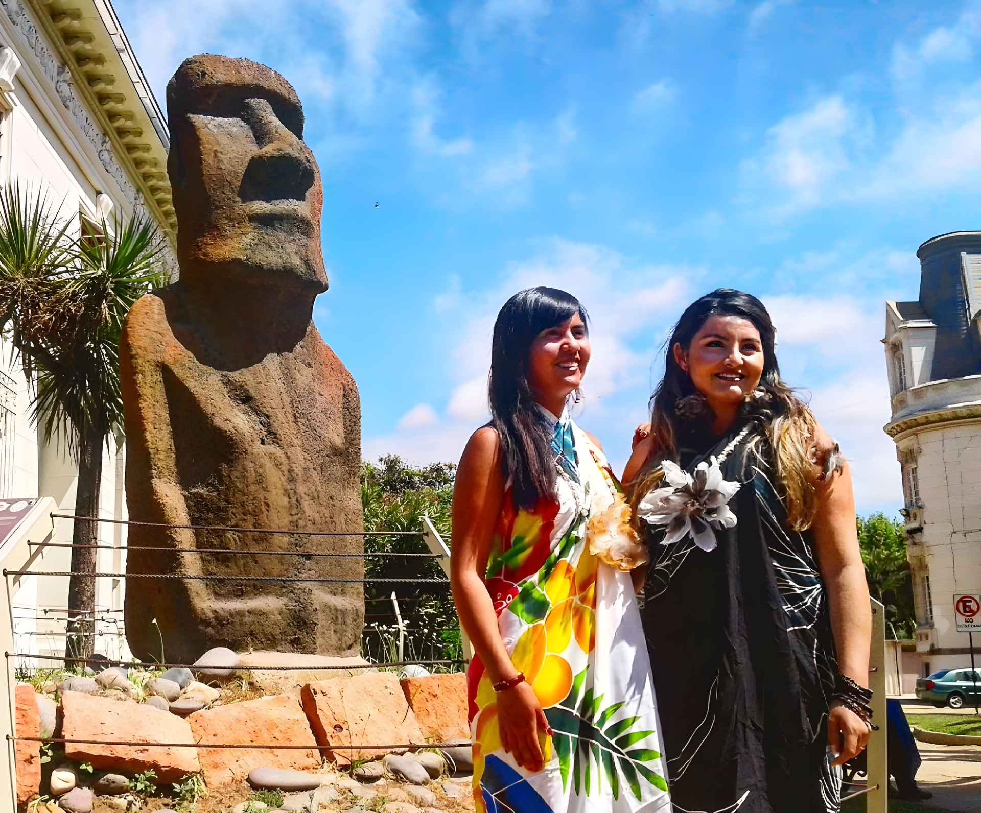 Two girls dressed in Easter Island outfits in front of the original statue of a moai in Viña del Mar